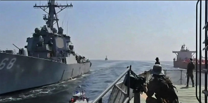 オマーン湾で米国の戦艦（左）とベトナム船籍の石油タンカー（右）を監視するイラン革命防衛隊海軍の部隊。イラン国営テレビが2021年11月3日に放送した映像からキャプチャー画像。イランは、今年10月下旬に国連国際海事機関（IMO）が主催する年に一度の「世界海事デー」に合わせてテヘランで海事に関するイベントを開催すると提案していたが、同国がアラビア湾において商用船舶の拿捕を繰り返していることを理由にその提案は無効とされた。（AFPファイル写真）