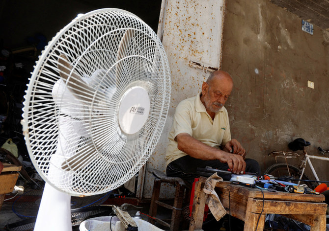猛暑の中、自身の店で扇風機を修理するパレスチナ人のムスタファ・アブドゥさん。2023年7月25日、ガザ市のシャティ難民キャンプ。（ロイター）