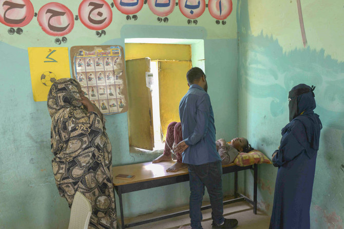 ボランティアが学校の建物に設置した仮設救急処置室で患者の傍に立つ親族たち。対立する二人の将軍の軍隊の間の戦闘が続く2023年5月27日、首都ハルツームの双子都市オムドゥルマン。（AFP）
