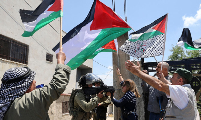 ヨルダン川西岸地区イスラエル占領地で、デモの後を追うイスラエル兵士と向かい合うデモ参加者（AFP）