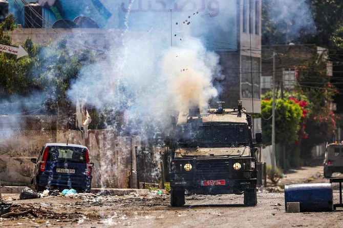 2023年7月4日、占領下のヨルダン川西岸都市ジェニンで進行中の軍事作戦中、装甲車両から催涙ガス弾を発射するイスラエル兵士。（AFP）