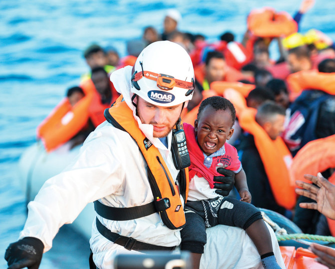 2016年11月5日、リビア沖のトパーズ・レスポンダー号による146人の移民・難民の救助活動中、マルタのNGO「MOAS」の救助隊員が赤ん坊を抱えている様子。アフリカ、アジア、中東からの移民や難民は、より良い暮らしを求めて危険な渡航を試みている。（AFP/資料）