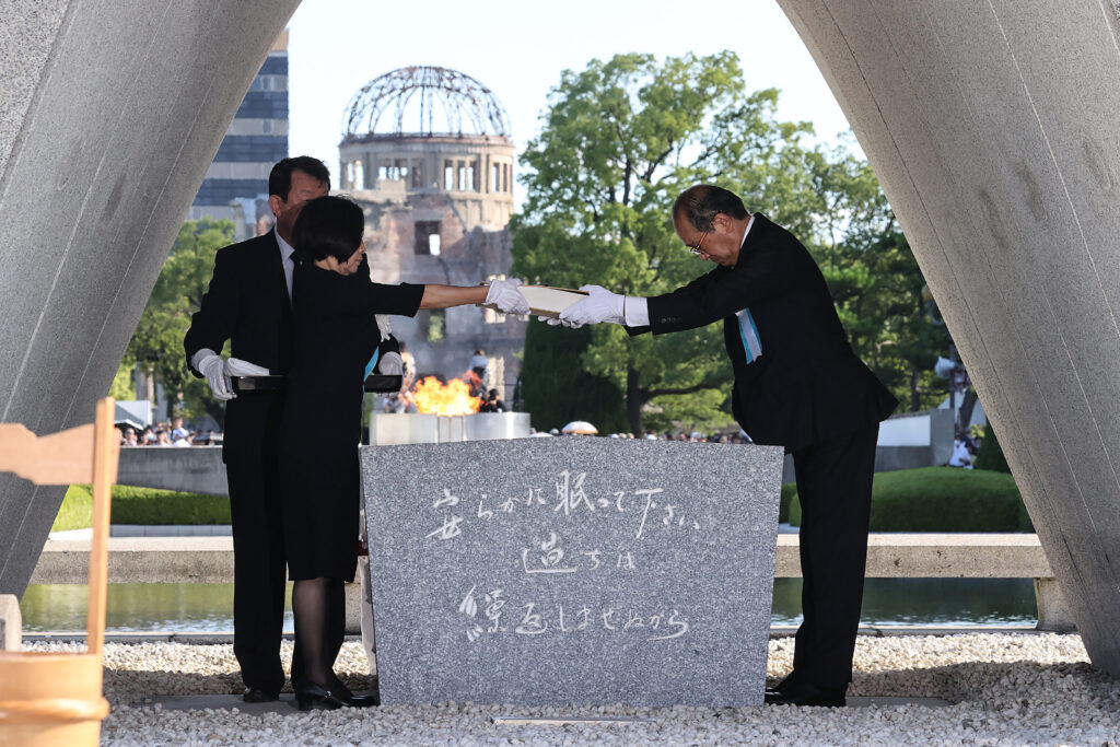 8月6日、広島市の平和記念公園で行われた、世界初の原爆投下から78年目の節目となる式典で、慰霊碑に原爆犠牲者名簿を安置する松井一實広島市長（右）と遺族代表。（AFP）