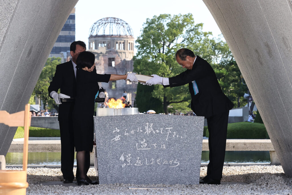 8月6日、広島市の平和記念公園で行われた、世界初の原爆投下から78年目の節目となる式典で、慰霊碑に原爆犠牲者名簿を安置する松井一實広島市長(右)と遺族代表。(AFP)