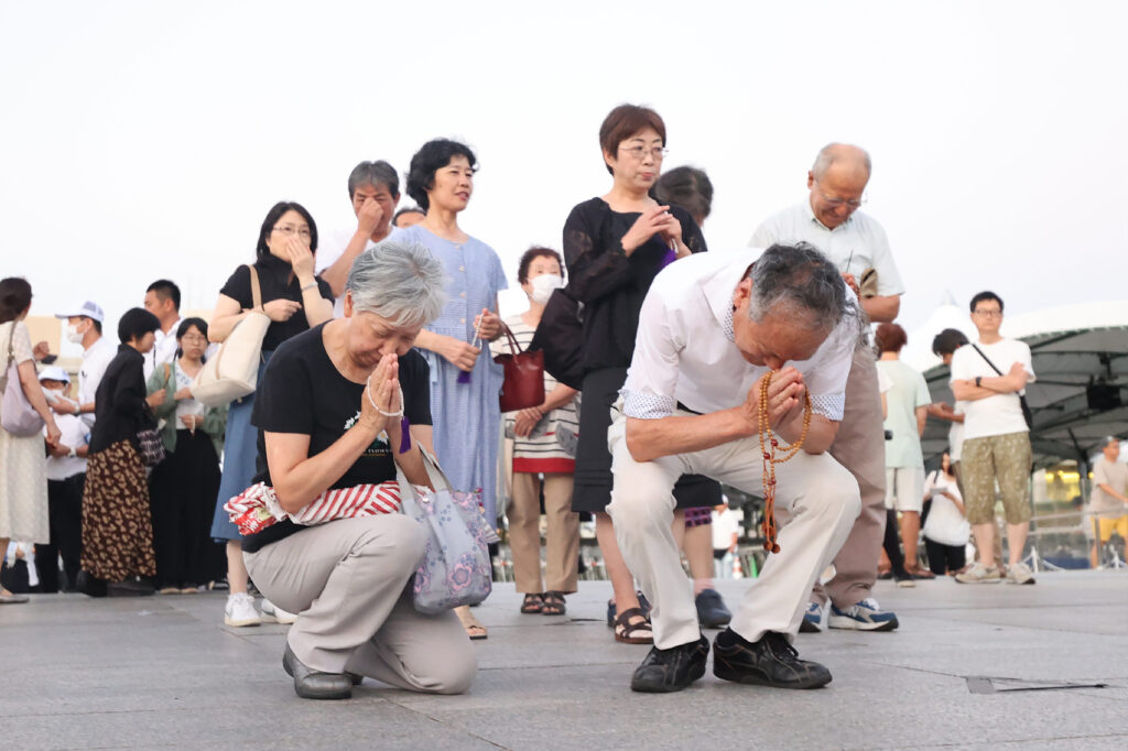 8月6日、広島市の平和記念公園にある原爆慰霊碑を訪れ、祈りを捧げる人々。（AFP）