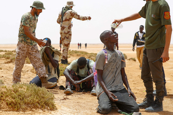 2023年7月30日、リビア・チュニジア国境のアルアッサー付近の無人地帯に到着後、チュニジア当局に放置されたされるアフリカ系移民に水を提供するリビアの国境警備隊の隊員たち。(AFP）