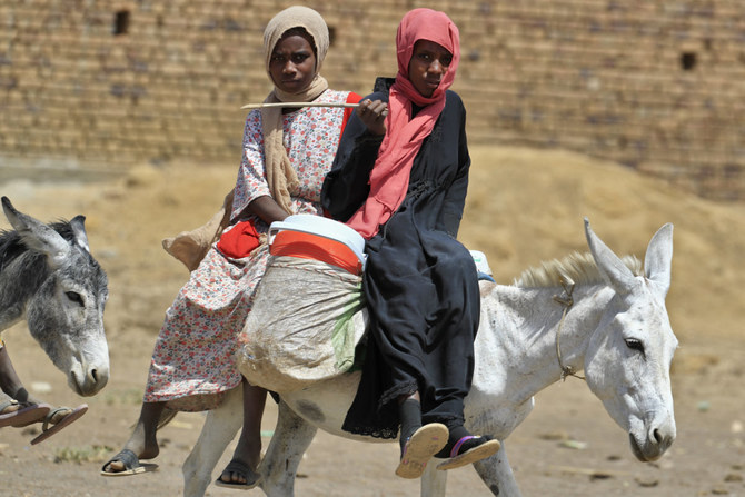 スーダンの首都ハルツームで、暴力から逃れるためにロバに乗るスーダンの女性たち。（AFP/ファイル）