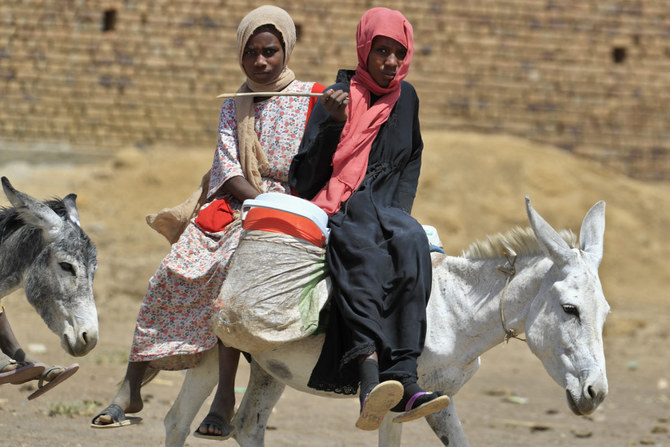 スーダンの首都ハルツームで、暴力から逃れるためにロバに乗るスーダンの女性たち。(AFP/ファイル)