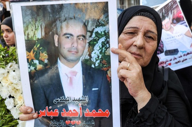 2020年のベイルート港爆発から3年目となった2023年8月4日、ベイルートにある司法宮の外で犠牲者の写真を掲げる犠牲者家族の一人。（AFP）