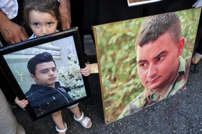 2020年のベイルート港爆発から3年目となった2023年8月4日、ベイルートにある司法宮の外で犠牲者の写真を掲げる犠牲者家族の一人。（AFP）