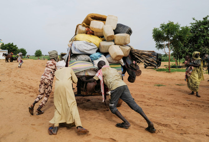 チャドのアドレにて、スーダンのダルフール地域の紛争から逃れたスーダン人の持ち物を運搬する荷車の所有者のチャド人が、スーダンとチャドの国境を越えようとして荷車を押しているところ。2023年8月4日撮影。（ロイター）