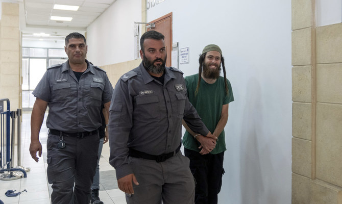 2023年8月8日（火曜日）、警官に手錠をかけられ、エルサレム地方裁判所に出廷した22歳のエリシャ・ヤレド（右）。ヤレド容疑者は、金曜日にヨルダン川西岸地区で起きたパレスチナ人男性殺害に関与した疑いで逮捕されたイスラエル人入植者2人のうちの1人である。（AP）