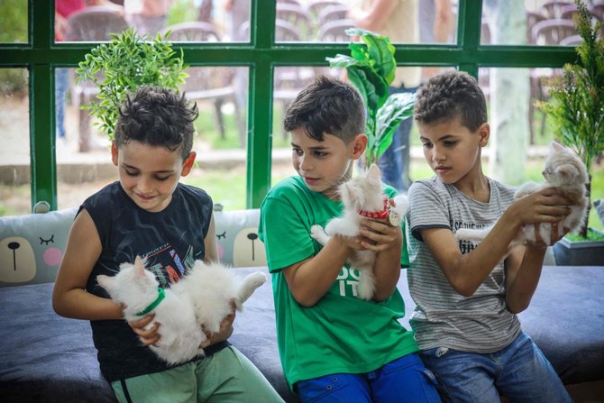 新しくオープンした猫カフェで猫を抱く男の子たち。ガザ市。(AFP)