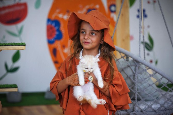 新しくオープンした猫カフェで猫を抱く女の子。ガザ市。（AFP）