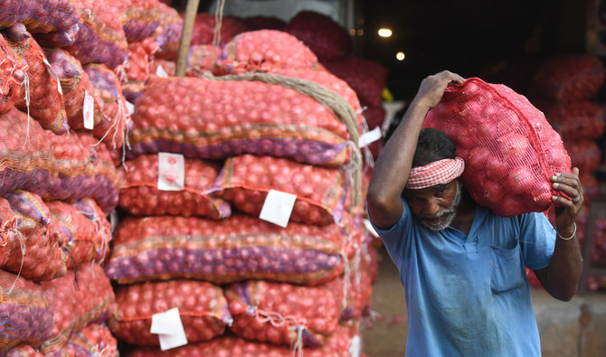 チェンナイの卸売市場でタマネギの袋を肩に担いでいるインド人労働者。2019年2月1日。（AFP）