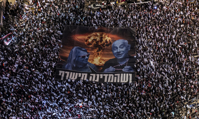 2023年8月26日、テルアビブにて、ベンヤミン・ネタニヤフ首相の政権による司法制度改革計画に反対する抗議運動のため、34週連続で集まるイスラエル国民。大きな横断幕には、ネタニヤフ氏と妻のサラ氏が描かれ、ヘブライ語で「この国を燃やせ」と書かれている。（AP通信）