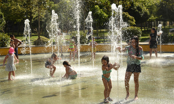 住宅に囲まれた庭で噴水の中に入って涼む子供たち。ジョージアの首都トビリシ。（AFP）