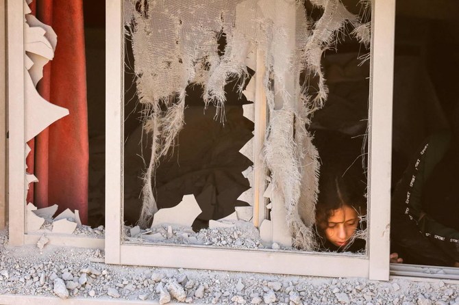 2023年8月8日未明、占領下にあるヨルダン川西岸地区のナブルス市東部に位置するパレスチナ難民のアスケル・キャンプで、イスラエル兵が破壊した家屋の壊れた窓から覗き込む少女。イスラエル軍は、2月末に占領下のヨルダン川西岸地区で2人のイスラエル人を殺害したとされるアブデル・ファタハ・クルーシャの家屋を破壊した。（AFP通信）