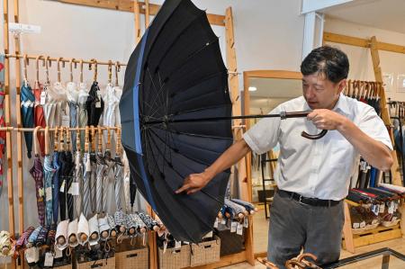 東京、東日本橋で1世紀近く雨傘を手作りしてきた小宮商店の店主、小宮宏之氏が店内で商品について語る。（2023 年8月3日撮影/AFP）