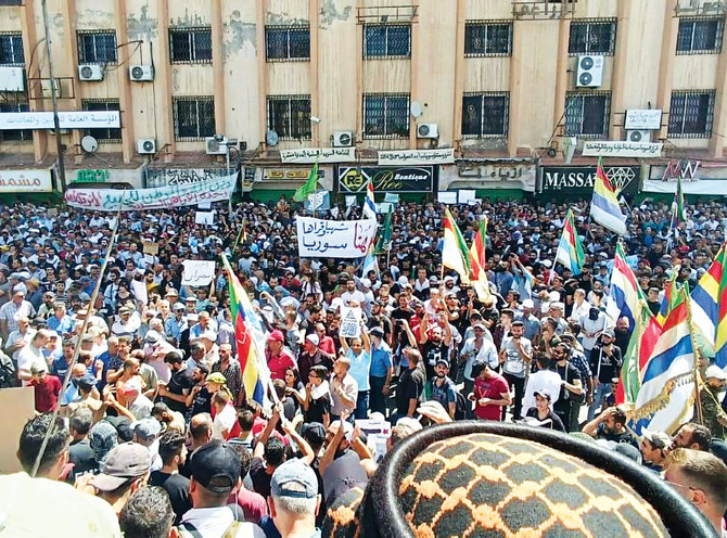 シリア南部の都市スワイダーで抗議活動に参加し、ドゥルーズ派の旗を振る数千人のシリア人たち。2023年9月15日。（AP）