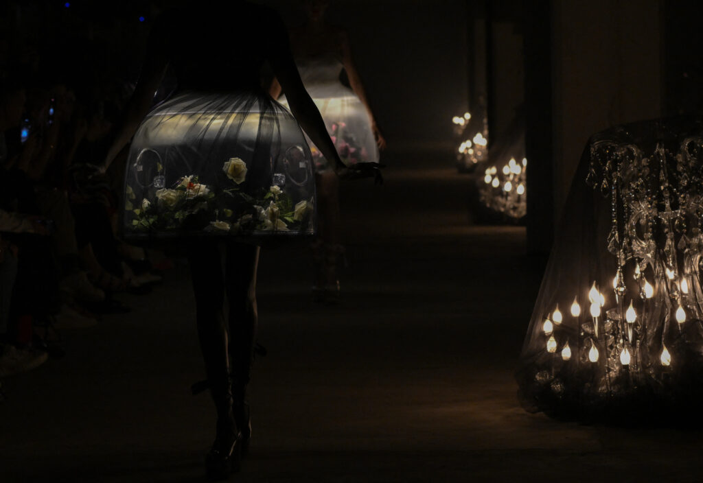 2024年春夏パリ・ファッションウィークのウィメンズコレクション、アンダーカバー（UNDERCOVER）のショーで、暗闇で光るドレスを着てランウェイを歩くモデルたち。(AFP＝時事）