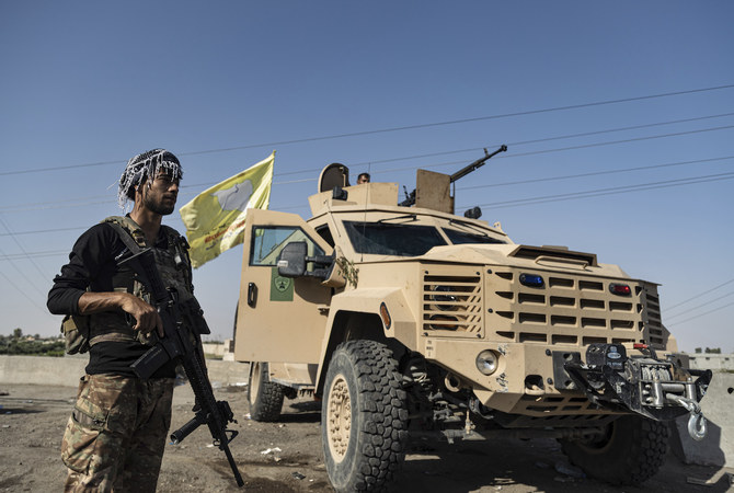シリアのデリゾール東部の田園地域、アル・サブハの町で装甲車両の隣に立つ、アメリカの支援を受けるSDFの戦闘員。2023年9月4日月曜日（AFP）