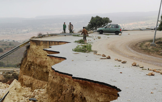 2023年9月11日、リビアのシャハット市を襲った強い嵐と大雨による洪水で、損壊した道路に立つ人々。(REUTERS)