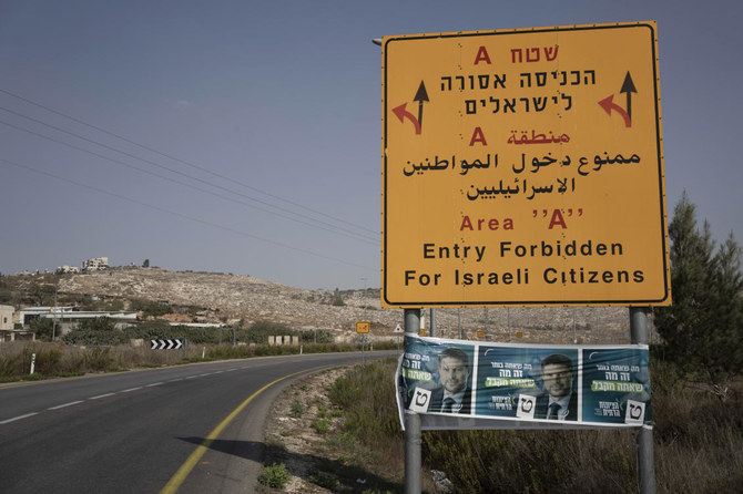 パレスチナ人統治区域の入り口を示す道路標識に張られた、イスラエルの極右議員ベザレル・スモトリッチ氏（現財務相）の選挙ポスター。ヨルダン川西岸地区の町ナブルス近郊。（AP）