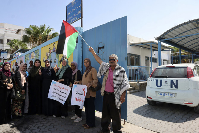 国連パレスチナ難民救済事業機関（UNRWA）が運営する保健施設の前で横断幕を手に座り込みを行い、パレスチナ難民への支援を削減しないよう同機関に要求する人々。ガザ市。（AFP）