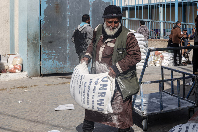 ガザ地区南部のラファ難民キャンプ、UNRWA配給センターにて、貧困家庭支援として受け取った小麦粉の袋を運ぶパレスチナ人たち。（File/AFP）