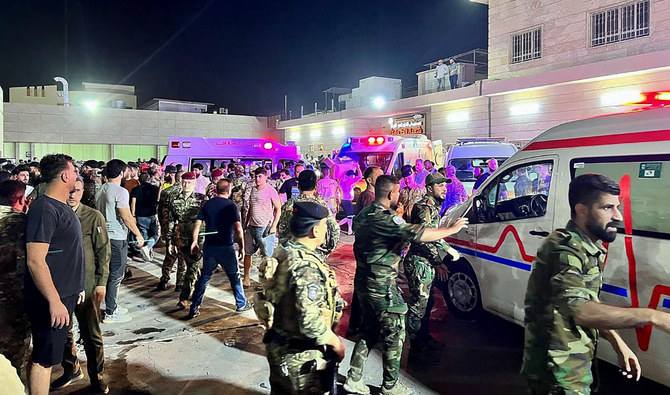 2023年9月27日、イラクのバクディダにあるハムダニヤ総合病院の前で、祝賀会中の結婚式場で火災が発生し、負傷者を乗せた救急車の周りに集まる兵士と救急隊員。(AFP＝時事）