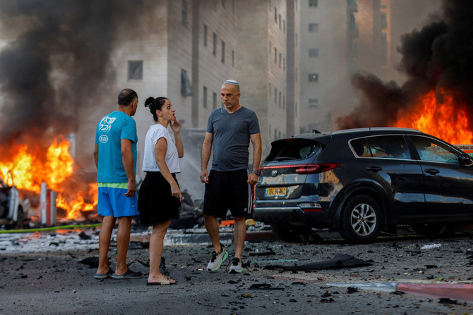 イスラエルのアシュケロンで、ガザ地区から発射されたロケット弾による火事の近くに集まる住民。2023年10月7日（ロイター）