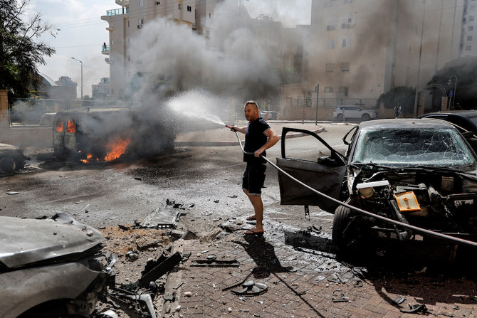 イスラエル南部アシュケロンでガザ地区からのロケット攻撃が続く中、燃えるバンを消火しようとする男性。2023年10月7日（ロイター）