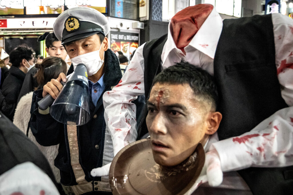 2022年10月31日、ハロウィーン期間中、東京・渋谷の街を歩く人々にメガホンで呼びかける警察官。(ファイル/AFP）