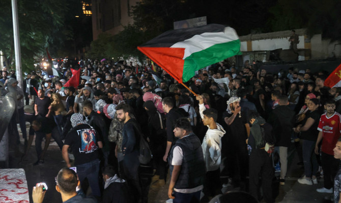 2023年10月18日、ベイルートのフランス大使館建物の入口での集会でパレスチナ国旗を振るデモ参加者たち。(AFP）