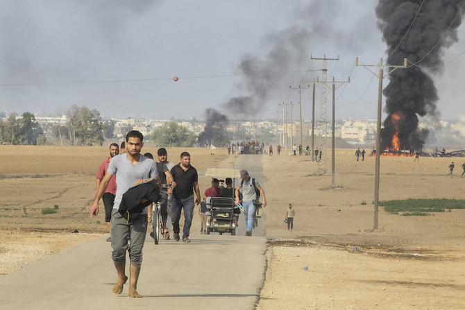 ガザ地区との隔離フェンス近くで、イスラエルのクファール・アザ・キブツから歩き去るパレスチナ人。2023年10月7日（AP）