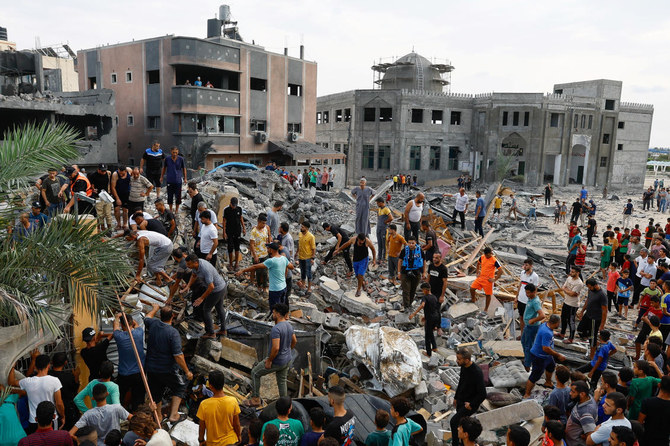 2023年10月9日、ガザ地区南部にて、イスラエルの攻撃で破壊された建物の瓦礫の中を歩くパレスチナ人たち。（ロイター）