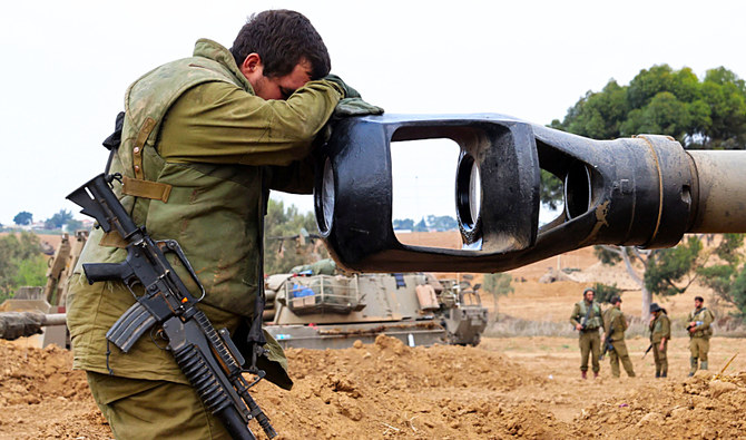 イスラエル兵がイスラエル南部のガザとの国境付近に陣取る中、装甲車の砲身に頭を預けるイスラエル兵。(AP)