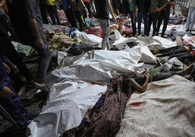 2023年10月17日、ガザ中心部のアフリ・アラブ病院へのイスラエル軍の空爆で死亡し、アル・シファ病院に搬送されたパレスチナ人の遺体の周りに集まる人々。(AFP＝時事）