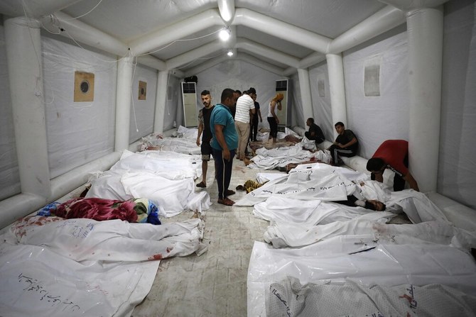 2023年10月17日、ガザ中心部のアフリ・アラブ病院へのイスラエル軍の空爆で死亡し、アル・シファ病院に搬送されたパレスチナ人の遺体の上に立つ人々。(AFP＝時事）