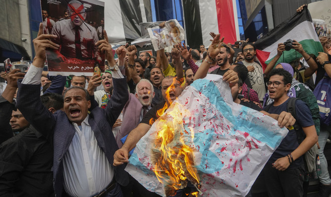 2023年10月18日水曜日、エジプトのカイロにあるジャーナリスト・シンジケートの前で、パレスチナ人との連帯を示すデモの際にイスラエル国旗を燃やすエジプト人のデモ参加者たち（AP通信）