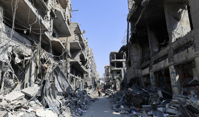 2023年10月24日、ガザ地区南部のハーン・ユニス。イスラエル軍の空爆で瓦礫と化した建物の間を、自転車を押しながら進んでいくパレスチナ人男性。(AFP通信/ファイル)