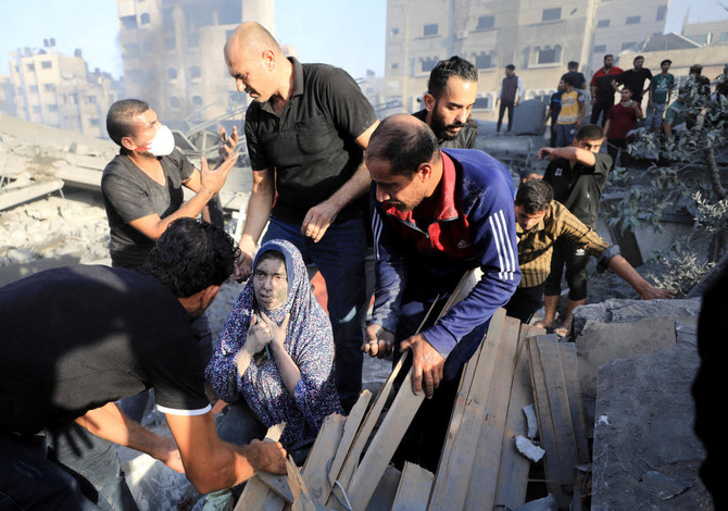 2023年10月25日、イスラエル軍の空爆でガザ市の住宅が破壊された現場で、死傷者を捜索するパレスチナ人女性と、彼女を手伝う人々。(ロイター)