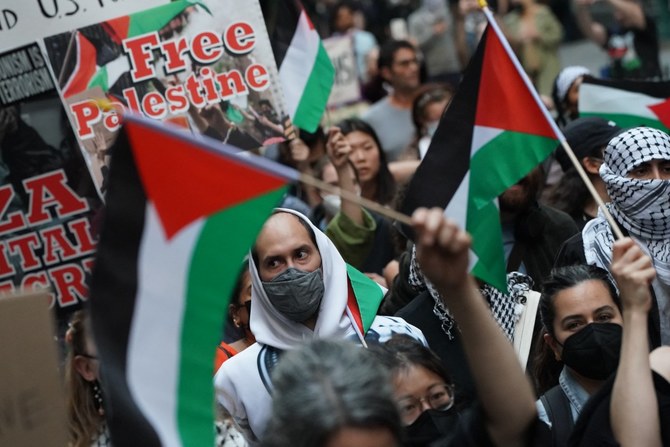 2023年10月26日、ニューヨーク証券取引所前で行われた「Flood Wall Street for Gaza」集会で、看板と旗を掲げるデモ参加者たち。(AFP)