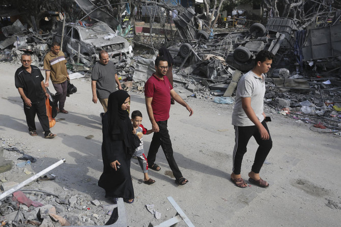 ガザ地区ラファでイスラエルによる爆撃後、破壊された建物の横を通り過ぎるパレスチナ人。2023年10月28日（AP）