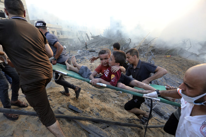 2023年10月25日、イスラエル軍がガザを空爆した直後、瓦礫の中から負傷した少年2人を助け出すパレスチナ人ら。(AP通信)