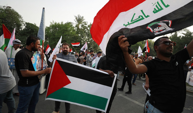2023年10月20日、バグダッドで行われた抗議デモで、プラカードを持ちパレスチナ国旗を振るイラク人。(AFP＝時事）