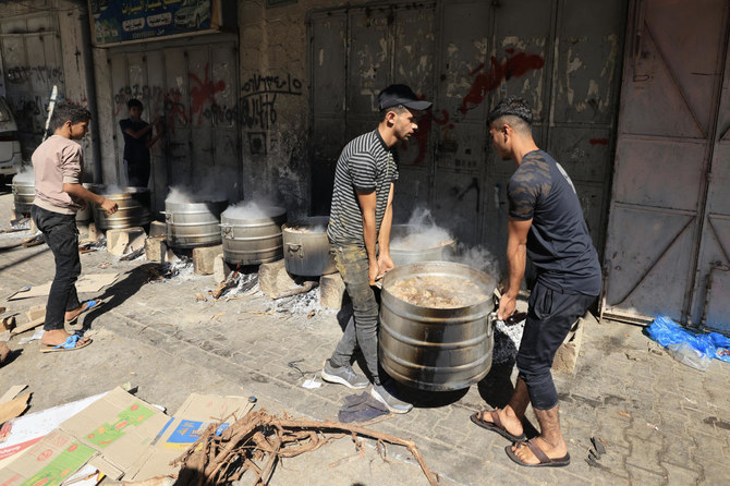 イスラエル軍の攻撃が続く中、燃料とガスの不足のため、薪で料理をして避難民になったパレスチナ人に食料を提供する人々。2023年10月15日、ガザ地区南部のハンユニスで。(資料写真/AFP)