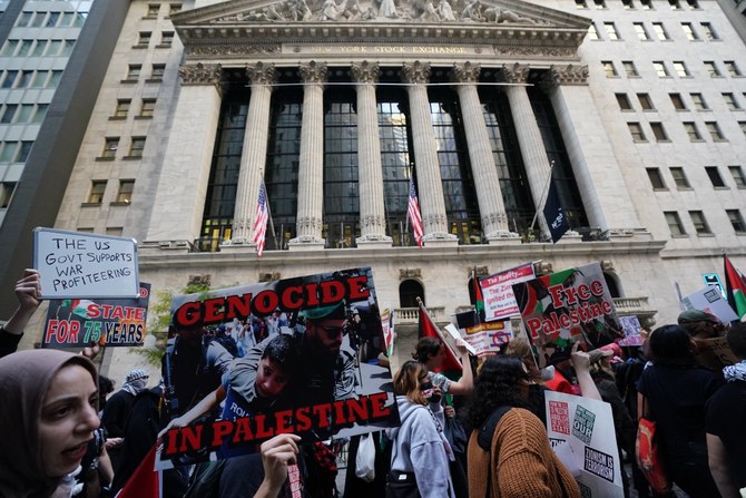 ニューヨーク証券取引所前で行われた「Flood Wall Street for Gaza」集会で、看板や旗を掲げるデモ参加者（AFP）