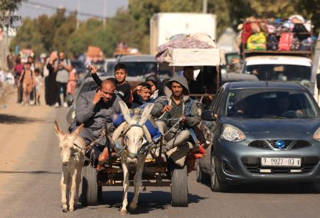 ガザ市で2023年10月13日、イスラエル当局が出した南部への退避勧告を受けて何百人ものパレスチナ人が荷物を持って避難する中、ロバの引く車に乗っている家族。（AFP）